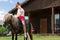 Cute little girl petting brown horse in the stable