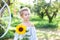 Cute little girl with pigtail on her head holds a sunflower. Childhood concept. Teenager girl with sunflower in garden. Child and