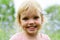 Cute little girl in a pink dress smiling in park