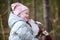 Cute little girl in pink hat and light blue jacket hugs Siberian Husky dog and smiling