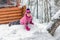 Cute little girl in pink sport suit having fun playing outdoors during snowfall in winter. Children winter seasonal outdoor