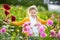 Cute little girl playing in blossoming dahlia field. Child picking fresh flowers in dahlia meadow on sunny summer day