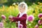 Cute little girl playing in blossoming dahlia field. Child picking fresh flowers in dahlia meadow on sunny summer day