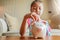 Cute little girl playing collect money with a pink saving Pig Jar