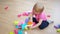 Cute little girl playing with colorful construction plastic blocks on the floor