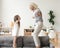 Cute little girl playing with grandmother jumping on couch toget