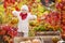 Cute little girl playing with pumpkins in autumn park. Autumn activities for children. Halloween and Thanksgiving time fun for