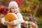 Cute little girl playing with pumpkins in autumn park. Autumn activities for children. Halloween and Thanksgiving time fun for