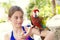 Cute little girl playing with a Scarlet Macaw Parrot