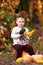 Cute little girl playing with vegetable marrow in autumn park. Autumn activities for children. Halloween and Thanksgiving time fun