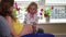 Cute little girl and pregnant mother play doctor with stethoscope sit on sofa