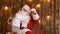 Cute little girl pulling Santa`s beard to check if it`s real sitting on his lap