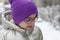 Cute little girl in a purple hat and glasses in winter park