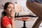 Cute little girl putting whoopee cushion on father`s chair while he sitting down at home, closeup