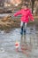 Cute little girl in rain boots playing with colorful ships in the spring creek walking in water