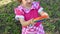 Cute little girl in red dress and baseball cap playing in nature with fidget pop It, flexible touch fidget toy with push bubble