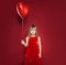 Cute little girl with red heart balloon on red background. Pretty child smiling, love, birthday and party celebration concept
