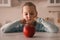 Cute little girl refusing to eat apple in kitchen