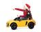 Cute little girl in Santa hat with Christmas tree driving children`s electric toy car on white background