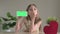 Cute little girl shows phone with green screen near red heart and sending air kiss