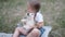 Cute little girl sits on the grass and holds a white puppy in her arms in the summer.