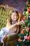 Cute little girl sits on a sofa near a festive Christmas tree