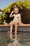 Cute little girl sitting on the edge of a swimming pool