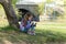 Cute little girl sitting on the grass with a mobile phone in her hands and sending message on phone mobile