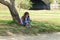 Cute little girl sitting on the grass with a mobile phone in her hands and stares at the phone\'s screen