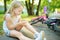 Cute little girl sitting on the ground after falling off her bike at summer park. Child getting hurt while riding a bicycle