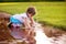 Cute little girl sitting in puddle