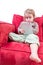 Cute little girl sitting on a sofa with a tablet