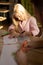 Cute little girl sitting by table while drawing picture with color highlighters