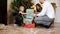 Cute little girl sitting underneath the christmas tree with her eyes closed while her father is bringing gift boxed