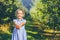 Cute little girl stands over blurred autumn garden background, extending big red apple in her palms to the camera