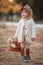 Cute little girl with a straw basket alone walks outdoors in a beautiful autumn park on a sunny day