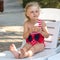 Cute little girl in swimsuit is sitting in deckchair and is eating ice cream