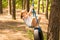 Cute little girl swinging on wheel attached to big tree in forest.