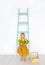 Cute little girl with tulips is in a light spring studio with ladder. Little beautiful princess.