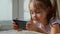 Cute little girl uses smartphone for online games and watching content.