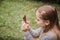 Cute little girl is using the smart phone. grass on background. On girl a hairpin with a pumpkin