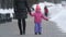 Cute little girl walking with her mother on winter street