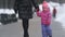 Cute little girl walking with her mother on winter street, daughter breaking out and going independently