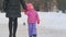 Cute little girl walking with her mother on winter street and turning her head staring at the sides