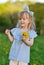 Cute little girl walking in the park with dandelion flowers