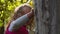 Cute little girl walks in the autumn forest with a tree. Child with curly blond hair in a pink vest on a blurred