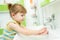 Cute little girl washing her hands in bathroom