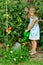 Cute little girl watering tomato and flowers in the backyard