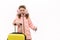 Cute little girl wearing pink fluffy earmuffs, down jacket and wool mittens, with suitcase and boarding pass, on white