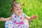 Cute little girl wearing polka dots dress sitting on the grass